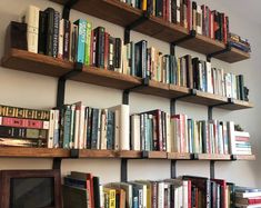 a bookshelf filled with lots of books next to a wall mounted computer monitor