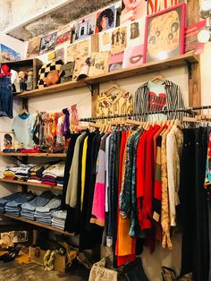 a clothing store with clothes hanging on shelves and other items in front of the wall