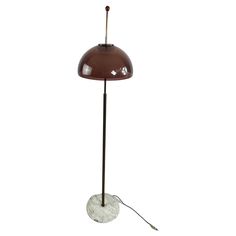 a floor lamp with a marble base and a brown shade on the top, standing up against a white background