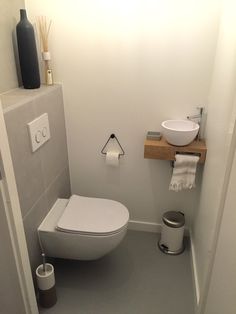 a white toilet sitting in a bathroom next to a wall mounted faucet and sink