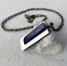 a necklace with a blue and white rectangle pendant hanging from it's chain