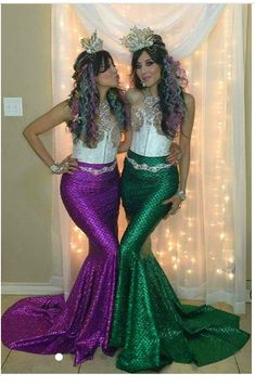 two women dressed in mermaid costumes standing next to each other with their hands on their hipss