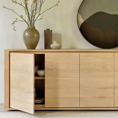 a wooden cabinet with two vases and a mirror on the wall behind it in a living room