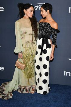 two women standing next to each other on a blue carpet