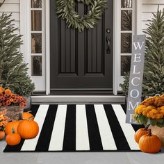 a black and white striped rug with pumpkins in front of a welcome sign on the front door