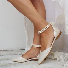 a woman wearing white shoes with pearls on the toes