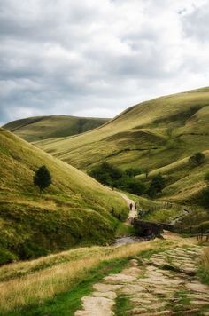 a dirt road going through a lush green valley