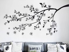 a living room filled with furniture and a tree branch wall decal on the wall