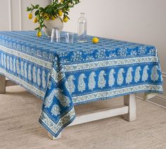 a blue and white table cloth with an elephant design on it, next to a potted plant