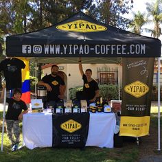 two men standing under a tent selling coffee