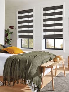 a bedroom with two windows covered in blinds