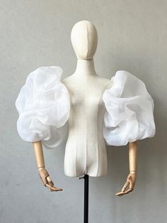 two mannequins with white ruffles on their arms and legs, one standing up