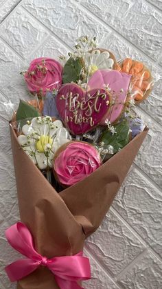 a bouquet of flowers wrapped in brown paper with a pink bow on the top and happy birthday written on it