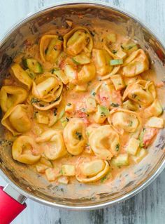 a pot filled with pasta and sauce on top of a wooden table