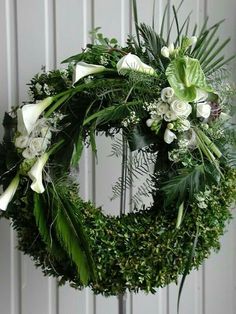 a green wreath with white flowers and greenery