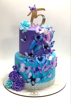 a purple and blue cake with butterflies on it's tiers is displayed in front of a white background