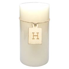 a white candle with a wooden initial on the front and a rope wrapped around it