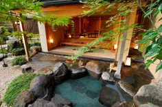 the inside of a japanese style house with rocks and trees around it, lit by lanterns