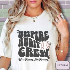 a woman wearing a t - shirt that says umpire adult crew with a baseball on it