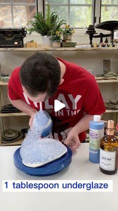 a man is pouring liquid into a heart shaped object on a table with other items around him