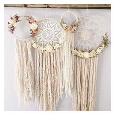 three macrame dream catchers hanging on a wall with flowers and lace around them