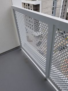 a white balcony railing with holes in the metal grating on it's sides