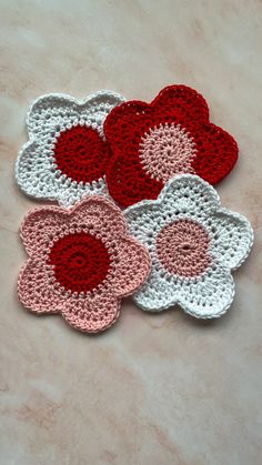 four crocheted flower coasters sitting on a table