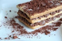 two pieces of chocolate covered dessert sitting on top of a white plate with powdered sugar