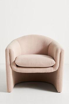 a pink chair sitting on top of a white floor next to a wall with a light colored background