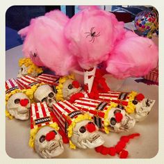 a table topped with lots of fake skulls covered in pink and yellow hair next to candy