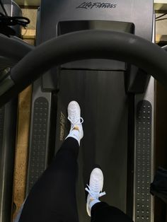 a person standing on a treadmill with their feet propped up against the machine's handle