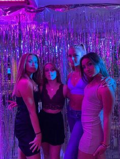 three women posing for a photo in front of purple and pink tinsel backdrops