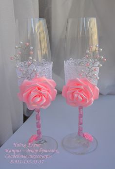 two wine glasses decorated with pink roses and pearls are sitting side by side on a table