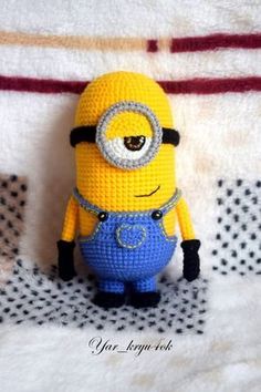 a crocheted minion sitting on top of a bed