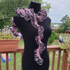 a mannequin wearing a pink and black scarf on top of a wooden table