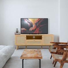 a flat screen tv sitting on top of a wooden stand in front of a white couch