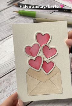 someone is holding up a card with hearts in an envelope on top of the card