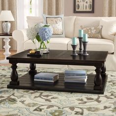 a living room with white furniture and blue flowers on the coffee table in front of it