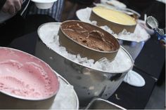 there are many different types of ice creams in buckets on the table together