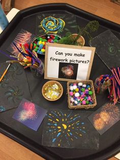 a table topped with lots of crafting items on top of a black tray next to a sign that says can you make firework pictures?