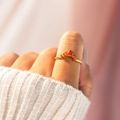 a woman's hand with a gold ring on it and a red diamond in the middle