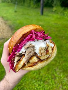 a hand holding a sandwich with meat and cabbage