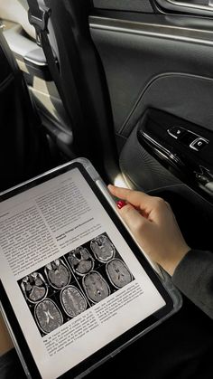 a woman is holding an electronic device in her hand and looking at the pages on it