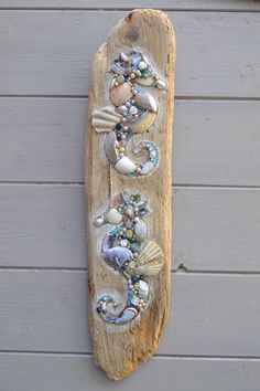 a wooden board with shells and seashells on it hanging from the side of a building