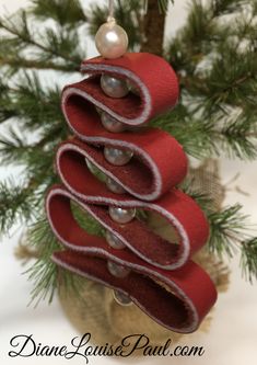 a christmas tree made out of red felt and silver buttons on top of a pine branch