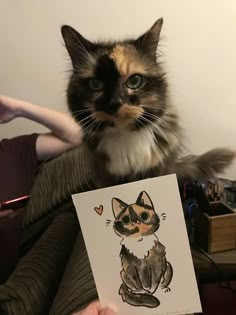 a cat sitting on top of a person's lap holding a card with an image of a cat