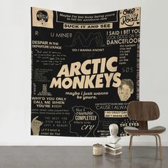 an arctic monkey's poster hanging on the wall next to a chair and table