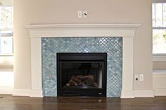 a fireplace in a living room with blue tile on the mantle and wood flooring