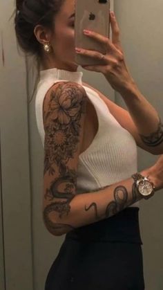 a woman taking a selfie in the mirror with tattoos on her arms and shoulder