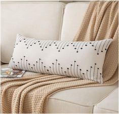 a white couch with a black and white pillow on top of it next to a blanket